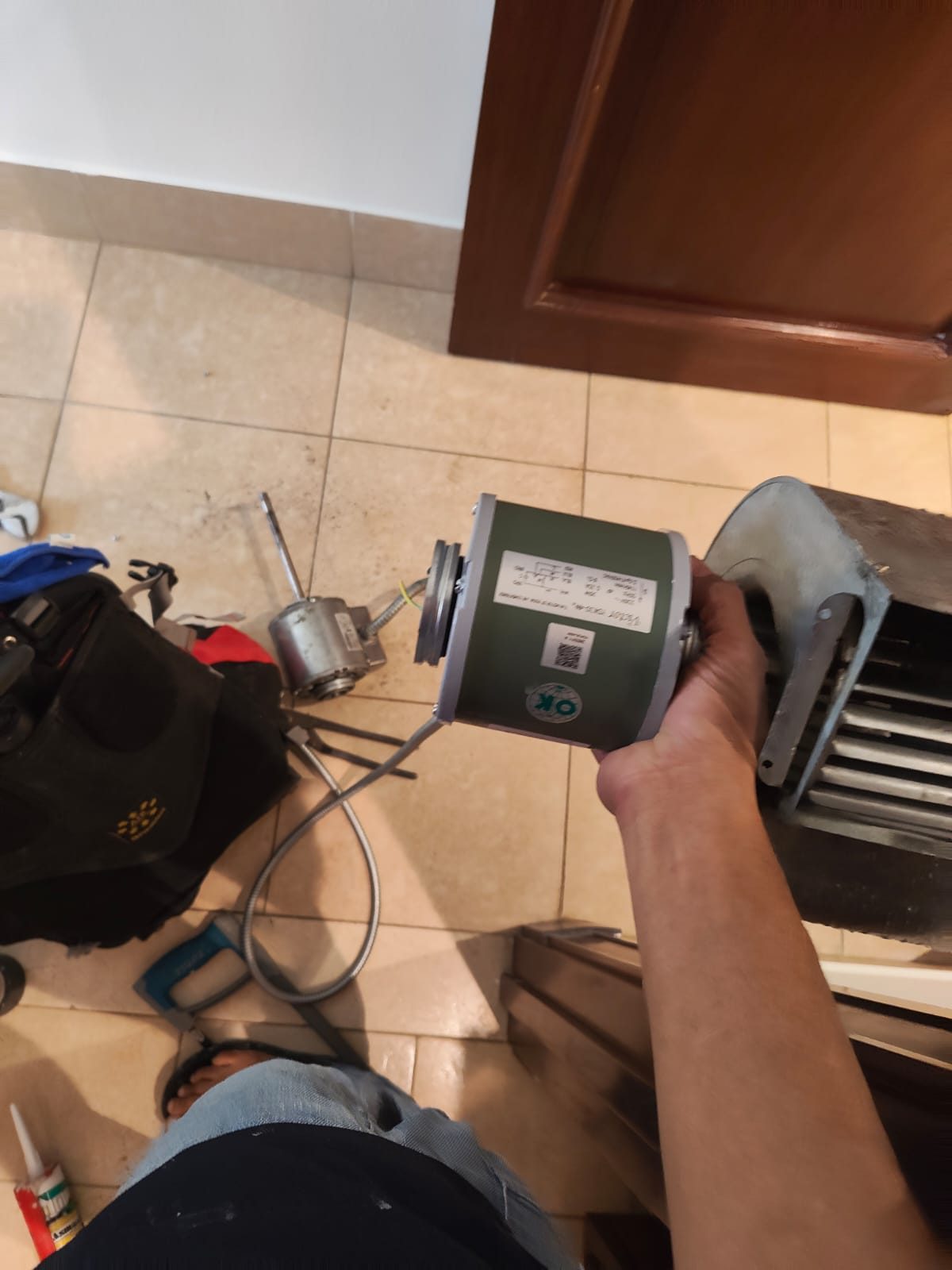 ARIA technician holding an AC fan motor during a maintenance visit