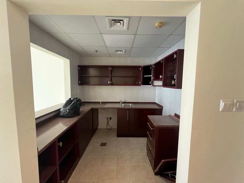 Old kitchen before the works, dark wood cabinets and mosaic tiles behind a serving hatch